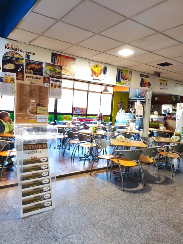 Entrada da Docemania Snack-Bar no D. Dinis, com a ementa num expositor de acrílico e cartazes dos pratos