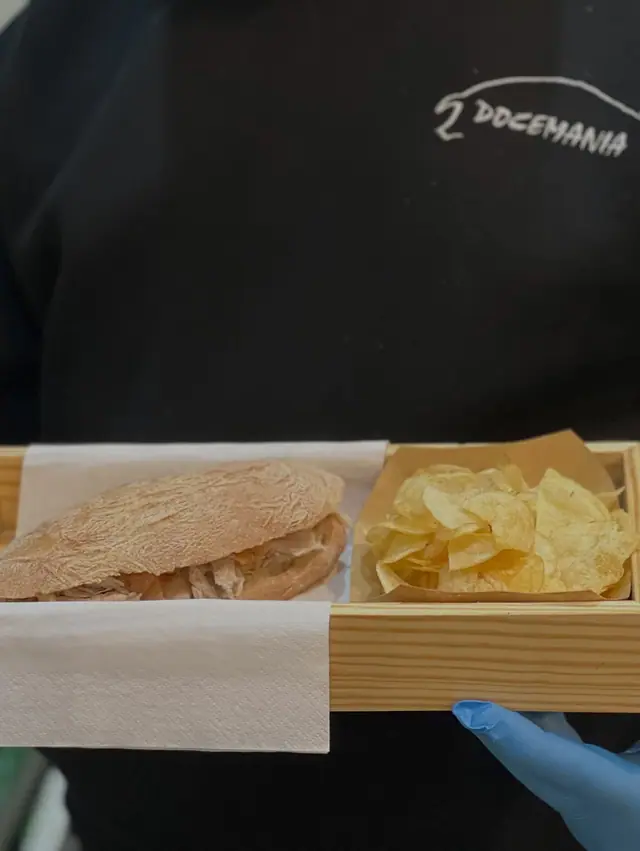 Funcionário da Docemania a segurar uma caixa com sandes de leitão e batatas fritas